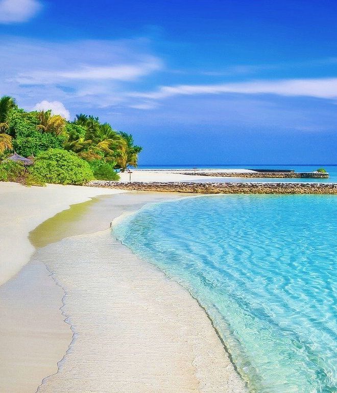Weißer Sandstrand mit Palmen an einer türkisblauen Lagune